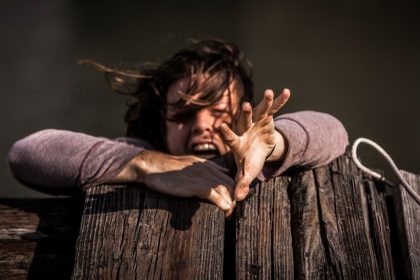 woman holding on brown wooden plank