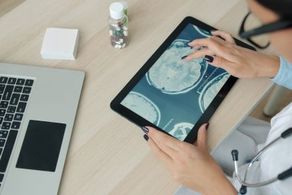 Doctor examining brain scan on tablet at desk.