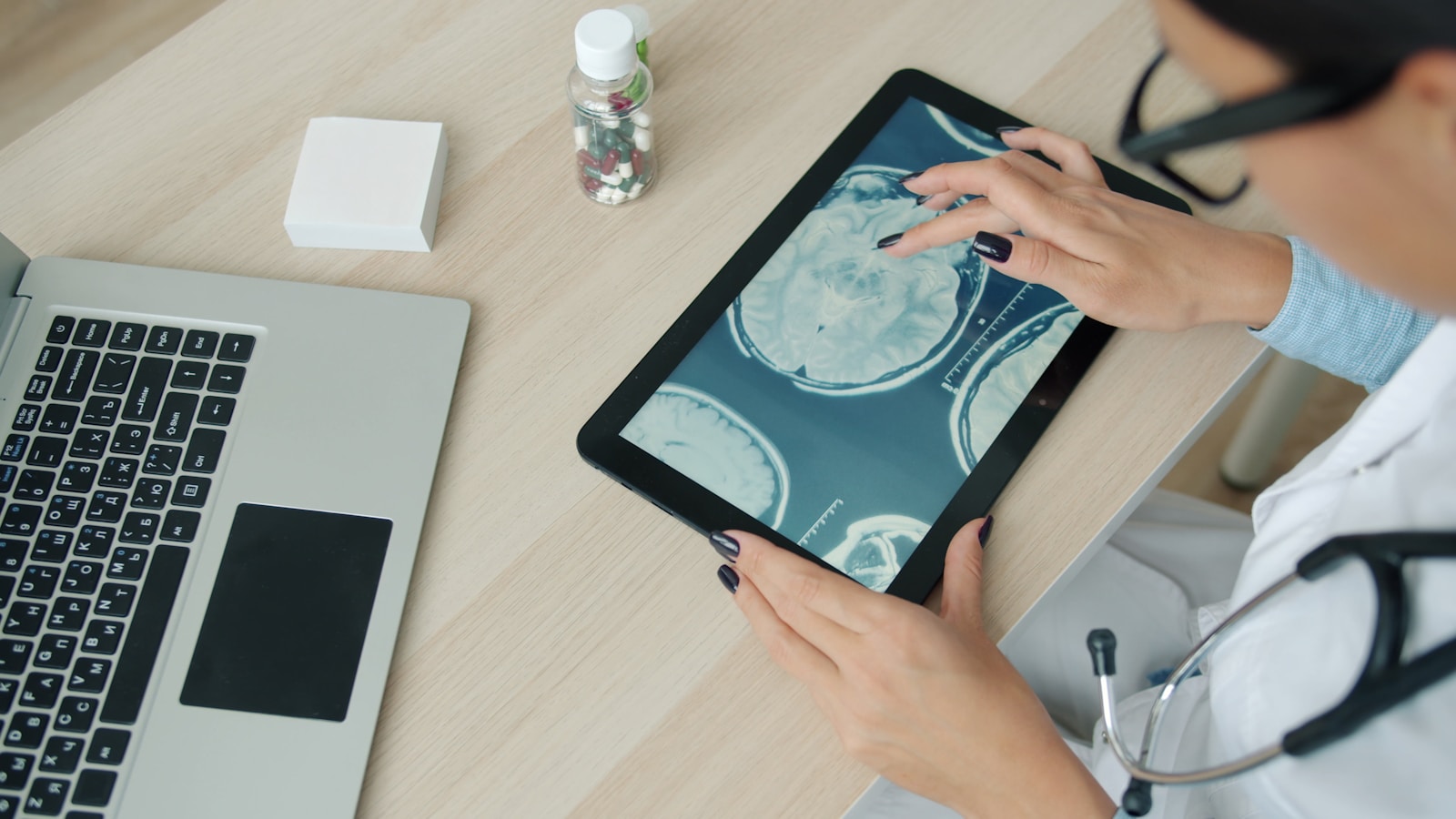 Doctor examining brain scan on tablet at desk.
