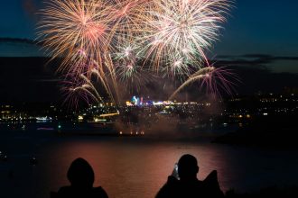 silhouette of two person taking photo of fireworks