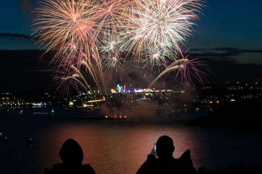 silhouette of two person taking photo of fireworks