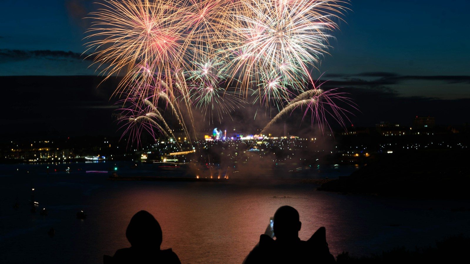 silhouette of two person taking photo of fireworks