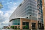 Modern glass building with curved entrance under sky.