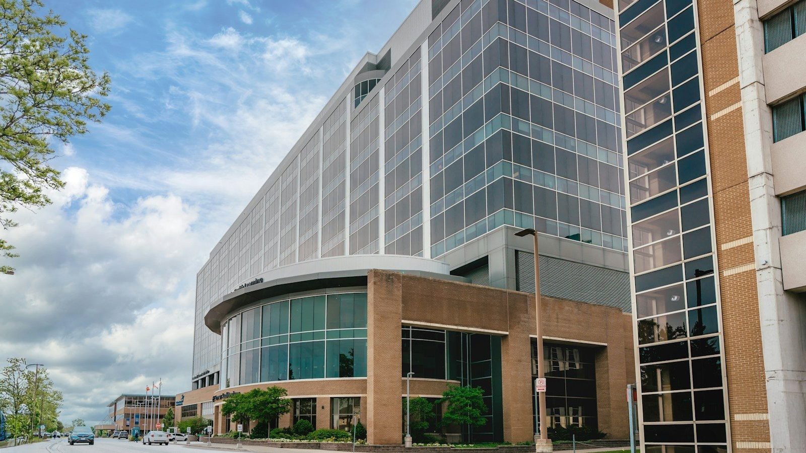 Modern glass building with curved entrance under sky.